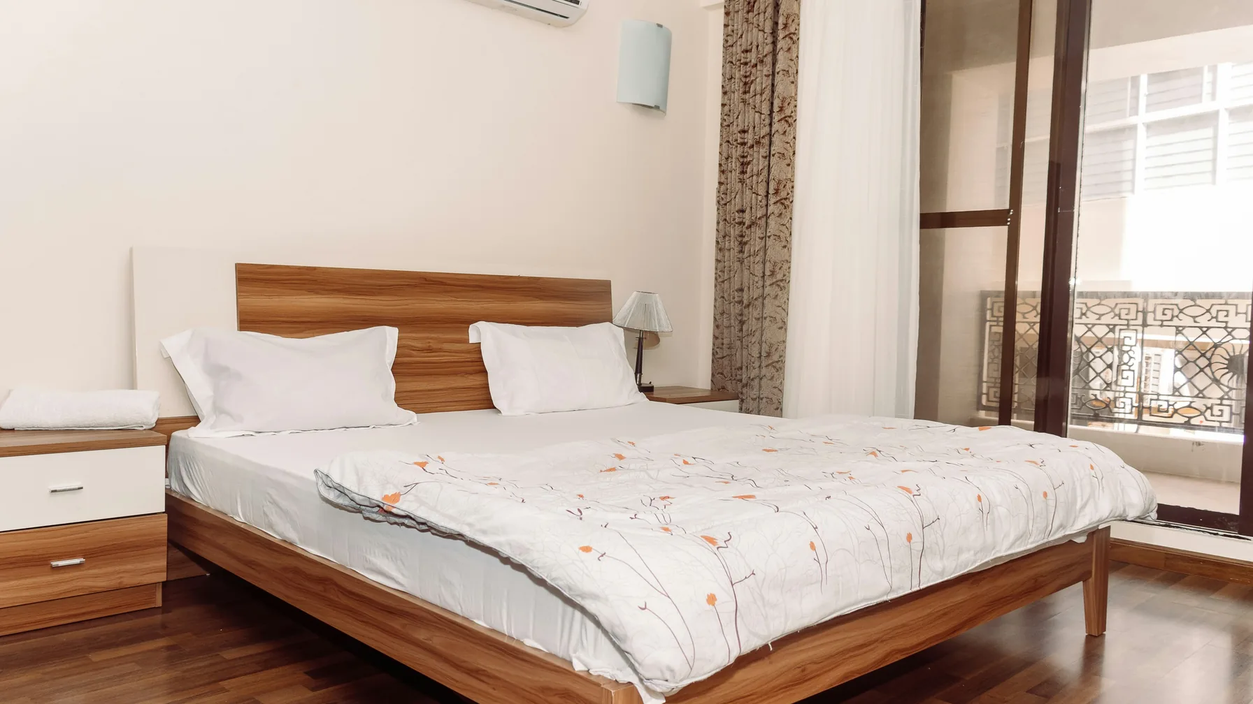 Bright, calm guest bedroom with natural light and a wooden bed.