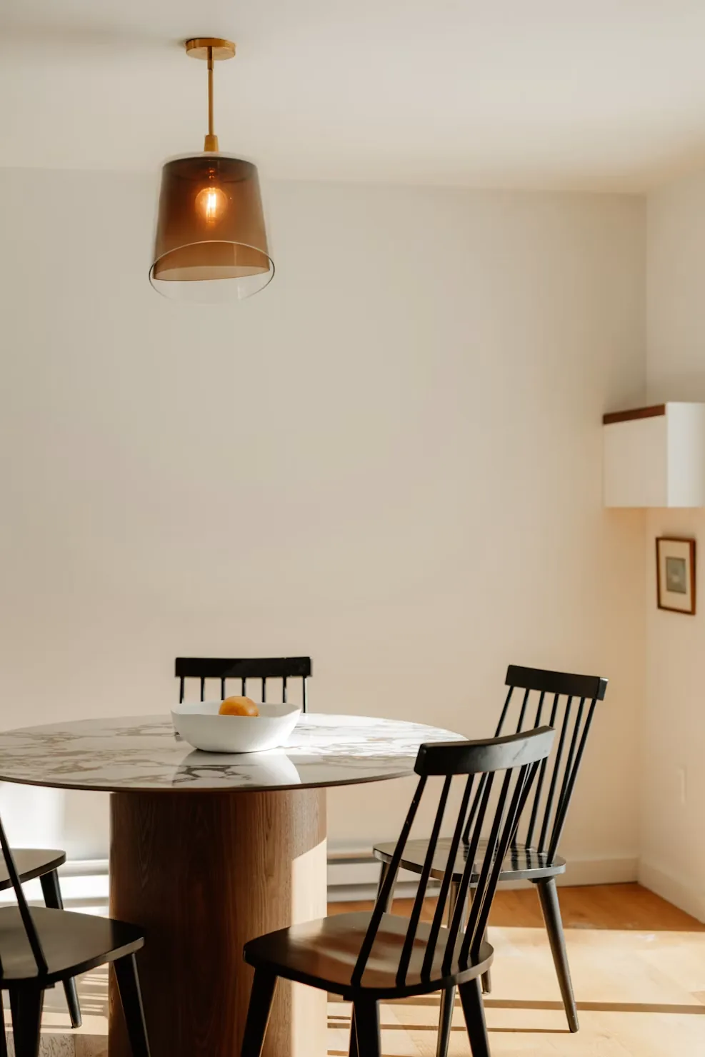 Round dining table and chairs in a sunlit room.