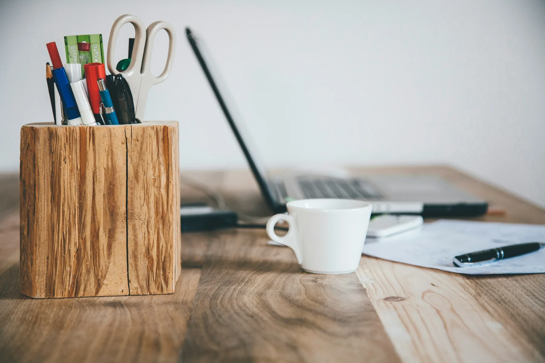 Organised host workspace with stationery, notebook and a white coffee mug.