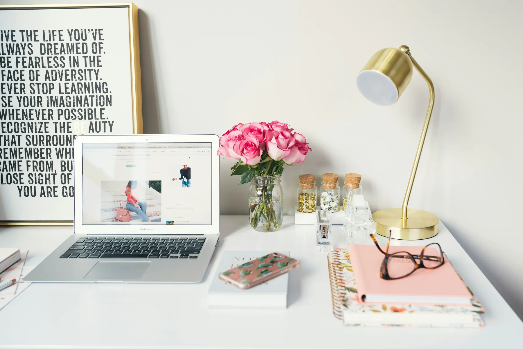Warm home workspace with laptop, notebooks and a brass desk lamp.